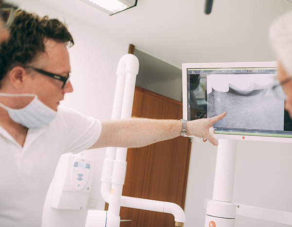 Endodontie - Zahnarzt zeigt auf eine Röntgenaufnahme in der Zahnarztpraxis Dr. Pfitzer in Stuttgart