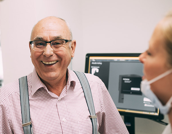 Zahnersatz - ein älterer Herr lacht in der Zahnarztpraxis Dr. Pfitzer in Stuttgart