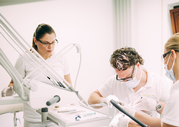 Zahnarzt Dr. med. dent. Hanns Joachim Pfitzer behandelt gemeinsam mit zwei Assistentinnen einen Patienten für eine bessere Mundgesundheit und eine neue Lebensqualität